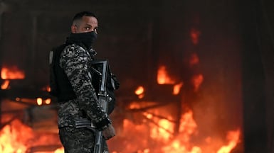 An officer stands next to a burning bus, allegedly set on fire by drug traffickers, during a police operation in Rio de Janeiro, Brazil. AFP