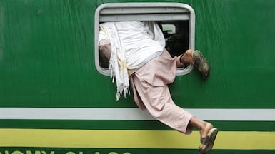 A passenger scrambles in through a train window, to travel home for Eid Al Fitr celebrations, at a station in Lahore, Pakistan. Reuters